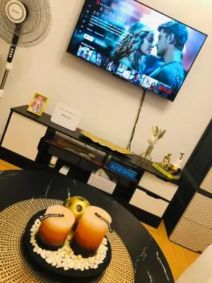 a living room with a table with a tv and two orange controllers at Avida Tower Sucat, comfortable studio type in Manila