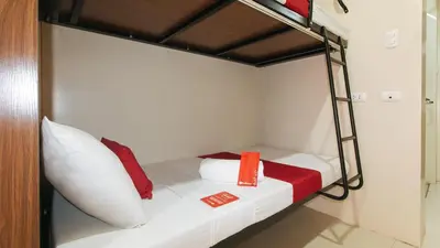 a bunk bed with red and white pillows on it at RedDoorz Plus near Nakpil St Taft Avenue in Manila