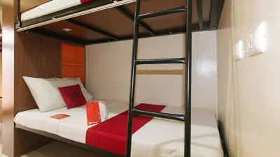 a bedroom with a bunk bed with a red blanket at RedDoorz Plus near Nakpil St Taft Avenue in Manila