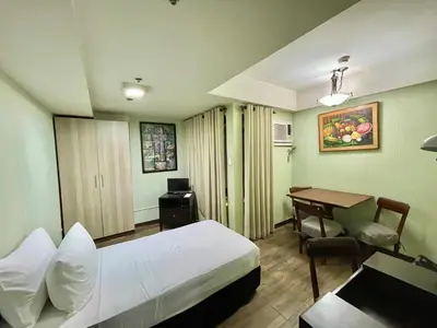 a hotel room with a bed and a desk and a table at CEO Flats in Manila