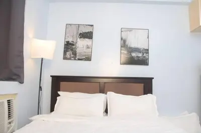 a bedroom with a bed with white sheets and pillows at A2J Executive Studio Suite Near Venice Mall BGC in Manila