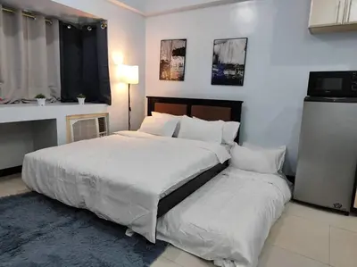 a bedroom with a large bed with white sheets and pillows at A2J Executive Studio Suite Near Venice Mall BGC in Manila