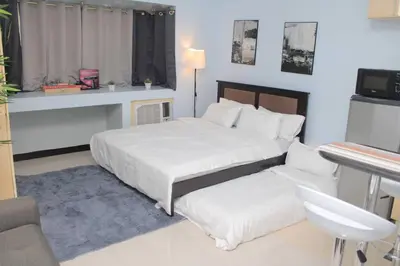 a bedroom with two beds and a table and a desk at A2J Executive Studio Suite Near Venice Mall BGC in Manila