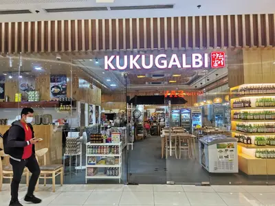 a man wearing a face mask walks past a kikuyuba supermarket at Ethan's Pad Nr. BGC in Manila
