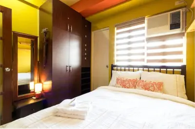 a bedroom with a white bed and a window at BalaiB1 Cozy Studio in Ortigas Center in front of Galleria in Manila