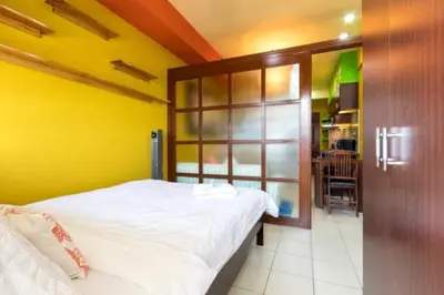 a bedroom with a white bed and a yellow wall at BalaiB1 Cozy Studio in Ortigas Center in front of Galleria in Manila