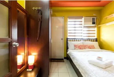 a small bedroom with a bed and a yellow wall at BalaiB1 Cozy Studio in Ortigas Center in front of Galleria in Manila