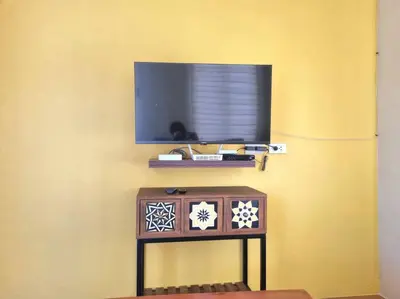 a tv on a yellow wall with a table with a television at #30 Bel Air House by Red Door House Rental in Santa Rosa
