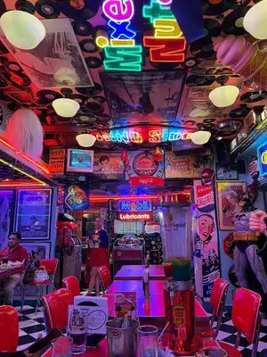 a room with neon signs and tables in a restaurant at Staycation by Ness in Ayala Makati in Manila