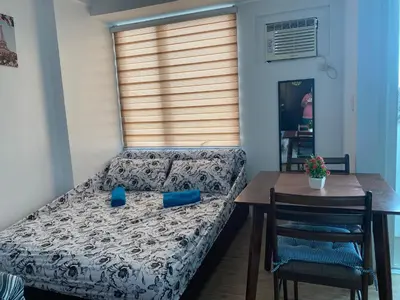 a bedroom with a bed and a table and a window at affordable staycation alabang in Manila