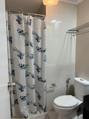 a bathroom with a toilet and a shower curtain at Telly's Studio Across NAIA3 in Manila