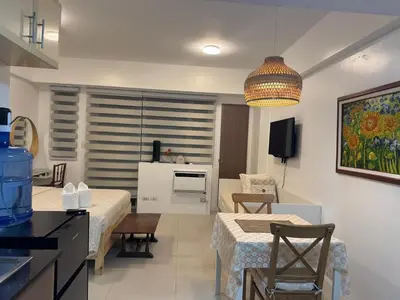 a kitchen and living room with two beds and a table at Telly's Studio Across NAIA3 in Manila