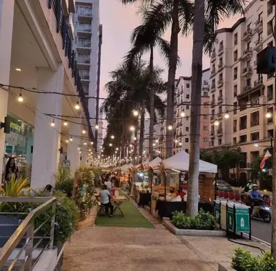 a street with palm trees and people sitting at tables at Telly's Studio Across NAIA3 in Manila