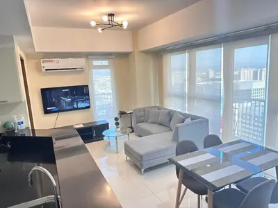 a living room with a couch and a tv at Premium Executive Suite at Venice Luxury Residences in Manila