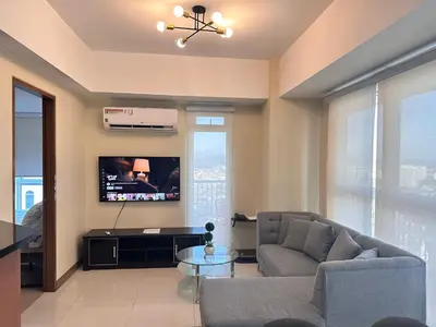 a living room with a couch and a tv at Premium Executive Suite at Venice Luxury Residences in Manila