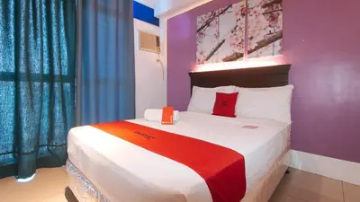 a bedroom with a large bed with red pillows at RedDoorz @ Melbourne Suites Makati in Manila