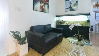 a living room with a leather couch and a fish tank at RedDoorz @ Melbourne Suites Makati in Manila