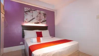 a bed in a room with a purple wall at RedDoorz @ Melbourne Suites Makati in Manila