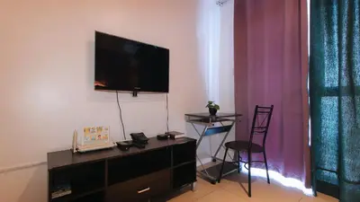 a living room with a flat screen tv on a wall at RedDoorz @ Melbourne Suites Makati in Manila