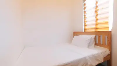 a small bedroom with a bed with white sheets and a window at RedDoorz @ Alquiza Residences Paranaque in Manila