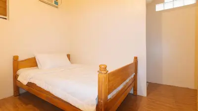 a bedroom with a wooden bed with white sheets at RedDoorz @ Alquiza Residences Paranaque in Manila