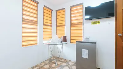 a room with a table and a tv and some windows at RedDoorz @ Alquiza Residences Paranaque in Manila