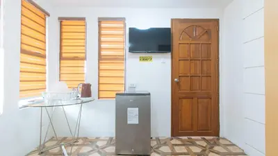 a room with a door and a table and a refrigerator at RedDoorz @ Alquiza Residences Paranaque in Manila