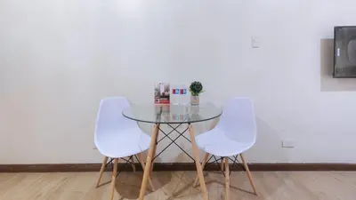 a glass table with two white chairs and a table at RedDoorz Plus @ Cuarto Verde Staycation in Manila