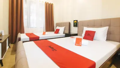 two beds in a hotel room with red and white sheets at RedDoorz Plus @ Cuarto Verde Staycation in Manila