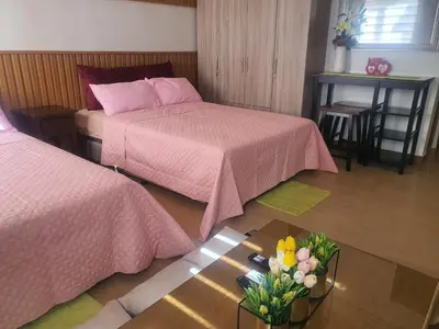 a bedroom with two beds and a table with flowers at Staycation ni Inday in Trece Martires