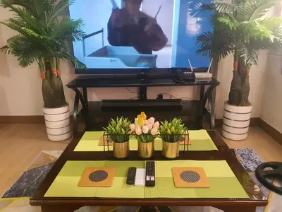 a living room with a table with flowers and a tv at Staycation ni Inday in Trece Martires