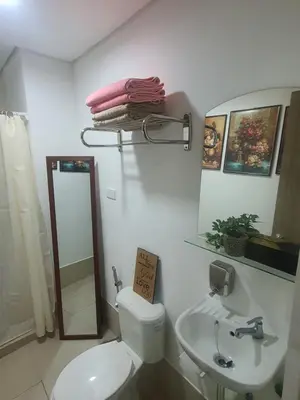 a bathroom with a toilet and a sink and a mirror at Staycation ni Inday in Trece Martires