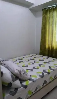 a bedroom with a bed with a comforter and curtains at Sea Residences Homey Condo by DNJ in Manila
