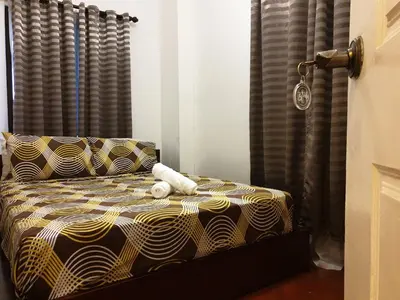 a bedroom with a bed with a yellow and black comforter at Raya P09 - Airport-Side Penthouse in Manila