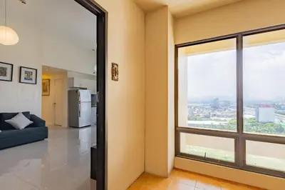 a living room with a large window and a couch at Raya P09 - Airport-Side Penthouse in Manila