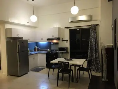 a kitchen with a table and chairs and a refrigerator at Raya P09 - Airport-Side Penthouse in Manila