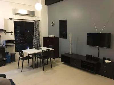 a living room with a table and a tv at Raya P09 - Airport-Side Penthouse in Manila