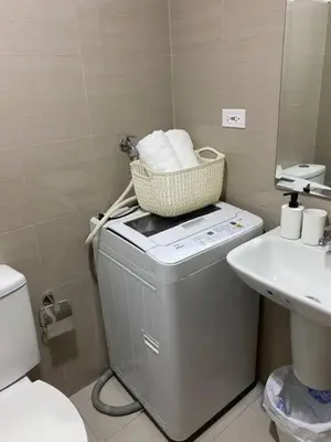 a bathroom with a toilet and a basket on top of a washing machine at Dtravellers Home 2 at SHORE 1 TOWER C (Near MOA) in Manila