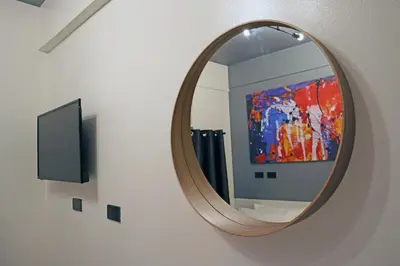 a round mirror on a wall with a painting at mySTAY Hotel BGC West in Manila