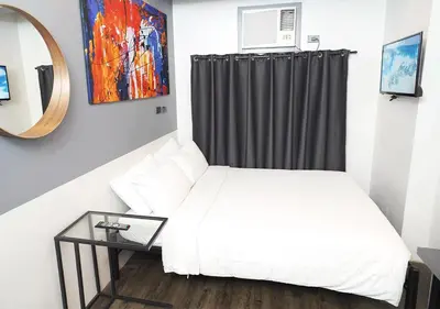 a small bedroom with a white bed and a mirror at mySTAY Hotel BGC West in Manila
