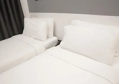 two beds in a room with white sheets and pillows at mySTAY Hotel BGC West in Manila
