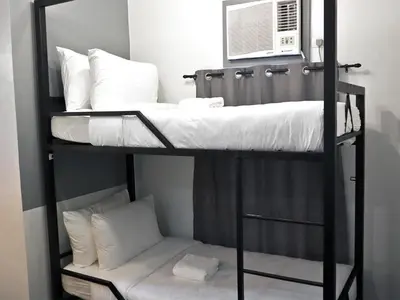 a black bunk bed with white pillows and a window at mySTAY Hotel BGC North in Manila