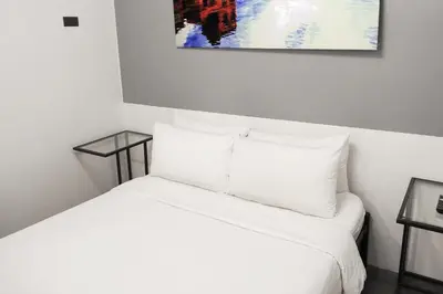a white bed with white pillows and a painting on the wall at mySTAY Hotel BGC North in Manila