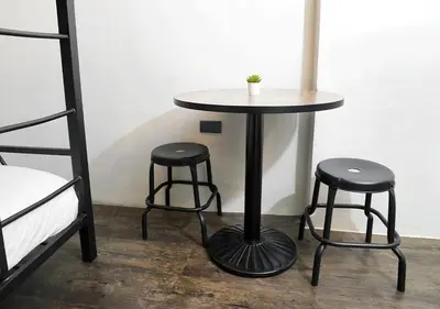 a table and two stools sitting next to a bed at mySTAY Hotel BGC North in Manila