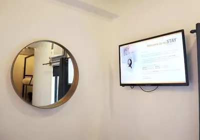 a mirror hanging on a wall with a television at mySTAY Hotel BGC North in Manila