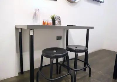 a table with two stools under it with a counter at mySTAY Hotel BGC North in Manila