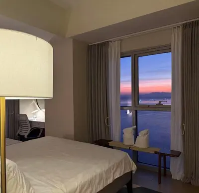 a hotel room with a bed and a large window at 1BRFacing ManilaBay SunsetNear Okada Solaire 1Park in Manila
