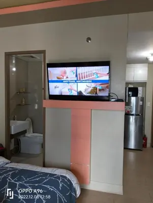 a flat screen tv on a wall in a bedroom at Rqui CondoTel Near Airport in Manila