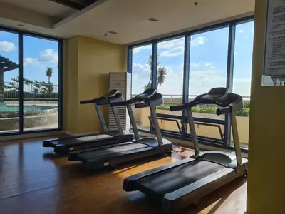 a row of treadmills in a gym with windows at SnugglePod Condotel - Grand Riviera Suites, US Embassy Manila, Roxas Blvd in Manila