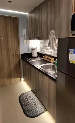a kitchen with a black refrigerator and a sink at LIGHT HOUSE ( MOA STAYCATION) in Manila
